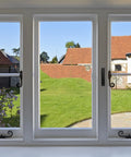View of green backyard with blue sky through large modern windows in a residential home setting.