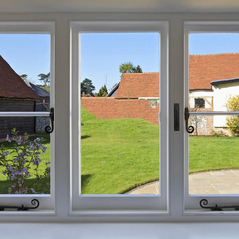 View of green backyard with blue sky through large modern windows in a residential home setting.