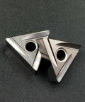Two triangular ceramic TNMG cutting inserts with center mounting holes for lathe turning