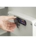 Person accessing battery compartment of in wall safe for home or biz with LED keypad and two manual override keys big interior