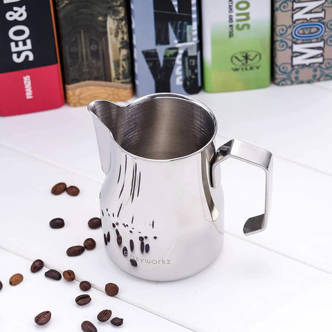 Stainless Steel 15 Ounce Espresso Steaming Pitcher For Milk Frothing And Latte Art With Dripless Spout Pro Grade Durable Anti Rust 304 Food Grade Milk Jug For Cappuccino on a table with coffee beans