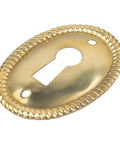 Vertical Oval Stamped Brass Keyhole Cover With Slick Retro Vibes, 1 By 1 1/2 Inch cabinet drawer escutcheon plate angled view.