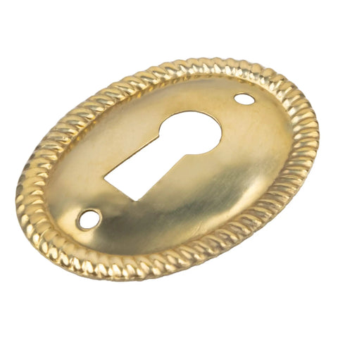 Vertical Oval Stamped Brass Keyhole Cover With Slick Retro Vibes, 1 By 1 1/2 Inch cabinet drawer escutcheon plate angled view.