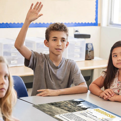 Student raising hand in class with Nine World Religions Poster Set For Social Studies Classrooms 12 By 18 Inches Ideal For K 12 Students.