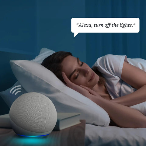 Woman in bed using voice command with Alexa-enabled smart speaker on nightstand.