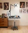 Smooth Rolling Adjustable Height Tattoo Workstation With Bright Led Panel And Smart Storage Rack For Your Professional Mobile Art Studio Daily Grind And Heavy Duty Gear, set up with art supplies and references.