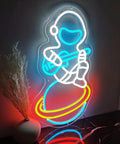 Spacecraft Neon Sign LED Wall Light For Bedroom And Kids Room Decor with astronaut design on planet, glowing colors.