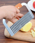 Crinkle-cut fry slicer with stainless steel blade and wooden handle, slicing a potato on a cutting board