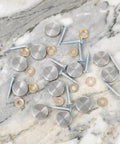 Heavy Duty Mirror Screw Caps With Stainless Steel Decorative Hardware Slick Silver Covers And Copper Silicone Washers Top Shelf Furniture And Glass Sign Fittings Built Like A Tank on marble background.