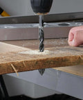 ZKH 10-piece cemented carbide masonry drill bit set drilling into a wooden plank on a metal worktable.