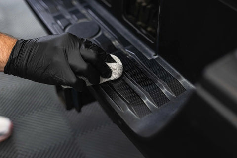 Armour Detail Supply Trim+ exterior plastics and rubber protectant applied to car trim with a black-gloved hand