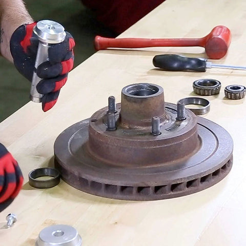 OEMTOOLS bearing race and seal driver set components on workbench with a rusty hub and two bearings