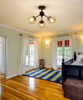 Three Light Glass Globe Chandelier Matte Black Nordic Style Semi Flush Mount Ceiling Fixture in a cozy bedroom setting.