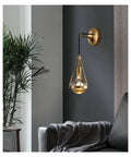 Slick Premium Copper LED Wall Sconce Featuring Glare Free Crystal Shade For Modern Bedroom Bedside Hallway And Staircase Decor With Tight Rust Proof Build And Killer Warm Ambient Glow mounted beside a couch with a blanket.