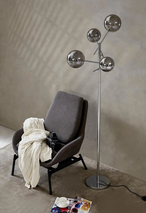 Sputnik 4 Light Floor Lamp With Smoky Grey Glass Globes, Chrome Finish beside modern chair in cozy living room setting