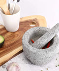 Large Granite Mortar And Pestle Set With 2 Cup Capacity Lid Silicone Lid Garlic Peeler And Anti Slip Base Pad Unpolished Granite Spice Grinder For Grinding Herbs And Spices Kitchen Must Have with chili peppers inside on a kitchen counter.