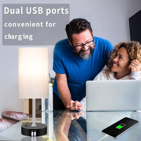Smart RGB LED Bedside Lamp With USB Charging Ports on table next to smiling couple using laptop, showcasing lamp's USB ports.