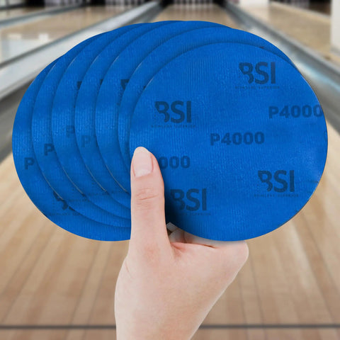 Person holding blue 1000 Grit Bowling Ball Sanding Disc Kit for Resurfacing Machines Ball Spinner and Hand Cleaning Pro Grade Pad