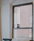 Adjustable Sliding Glass Door Security Bar in white finish installed vertically on a window, fits 16 to 51 inches.