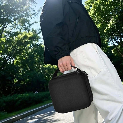 Person holding a black Slick Clutch Hard Shell Case For Travel Routers With Snug Mesh Pocket and Heavy Duty Zipper outdoors.