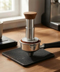 Straight Up 58mm Espresso Tamper For Dead On Pulls Daily Brushed Stainless Steel Coffee Press with wood grip, on a coffee mat.