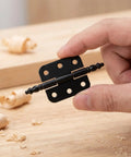 Close-up of a hand holding a hinge from the Vintage Wooden Box Hinges 10 Pcs Set Easy Install Iron Cabinet Hinges