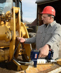 Worker using Lincoln 1884 PowerLuber 20V Battery Powered Grease Gun with 36 inch hose on heavy machinery outdoors.