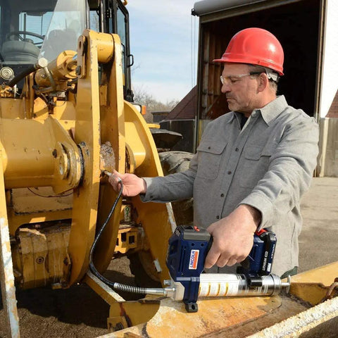 Worker using Lincoln 1884 PowerLuber 20V Battery Powered Grease Gun with 36 inch hose on heavy machinery outdoors.