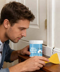 Person using Wall Repair Paste For Quick Fix And Seamless Finish, Waterproof Drywall Crack Filler for renovation on a door frame.