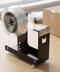 Heavy Duty Desktop Tape Dispenser With Solid Steel Base And Precision Serrated Blade For Straight Up Clean Cuts On Packing Boxes And Office Supplies No Sweat Desk Setup on a wooden desk.