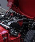 Engine bay of a red vehicle with hoses, showcasing Five Sixteenth Inch Fuel Line Hose For Cars And Trucks, SAE 30R10, Five Feet Long.