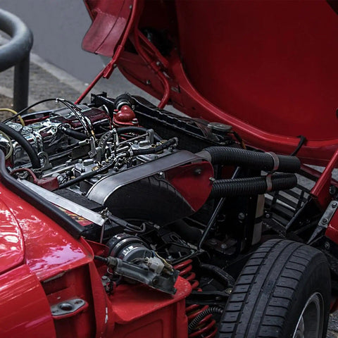 Engine bay of a red vehicle with hoses, showcasing Five Sixteenth Inch Fuel Line Hose For Cars And Trucks, SAE 30R10, Five Feet Long.
