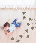 Child playing on floor with 64 Piece Dinosaur Footprint Floor Decals Peel And Stick Dinosaurs Wall Tracks Stickers for Baby Nursery Bedroom