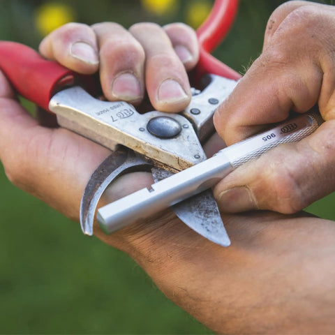 Person using Model 905 Sharpener Carbide Stone For Pruning Shears Pro Grade Honing And Sharpening Tool on pruning blades.