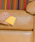 Hand using Chamois And Microfiber Cleaning And Polishing Pad For Countertops And Sinks 4 Inch By 1.75 Inch on leather surface