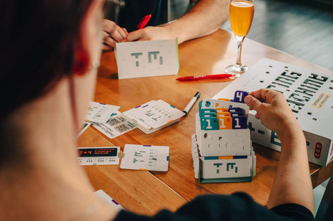 Players engaging with Analog Logic Puzzle Game For Teens And Adults Break Codes With Punch Card Challenges And AI Style Logic Puzzles