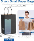 Black Kraft Paper Gift Bags With Handles 5.25 X 3.75 X 8 Inches Pack Of 20,000 next to phone for scale, man holding bags.