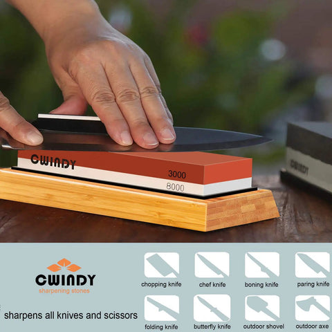 Person sharpening knife on Dual Sided Whetstone Knife Sharpening Kit with 400 1000 and 3000 8000 Grits Wet Stone Set, wooden base visible.