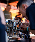 Barista preparing espresso drinks with a commercial coffee machine at an outdoor event