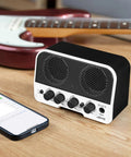 Portable 5W Bluetooth Guitar Amp For Practice With Dual 5W Speakers Clean And Overdrive Channels Rechargeable Battery AUX Input And Headphone Out Lightweight 330g 10W Peak Ideal For Bedroom Dorm Park Jams on table with phone and guitar