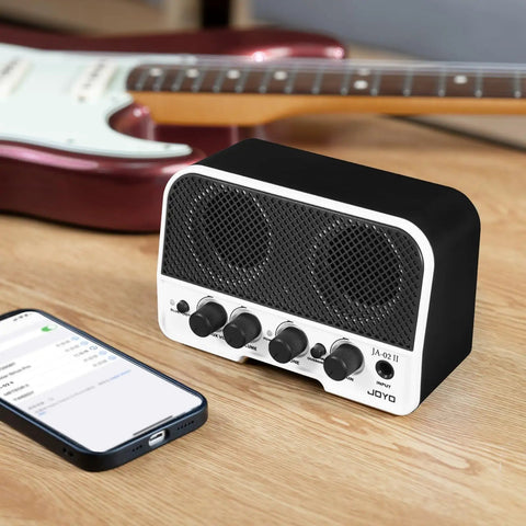 Portable 5W Bluetooth Guitar Amp For Practice With Dual 5W Speakers Clean And Overdrive Channels Rechargeable Battery AUX Input And Headphone Out Lightweight 330g 10W Peak Ideal For Bedroom Dorm Park Jams on table with phone and guitar