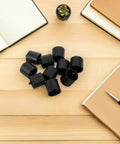 Plastic Tape Dispenser Core Replacement Inserts Pack Of 12 For Desktop Tape Machines Wear Resistant Wheel Core Accessories For Office And Stationery Supplies Durable Universal Fit For Most Desk Tape Dispensers Pro Grade Great For Home Office. Black plastic tape dispenser core inserts on a wooden desk.