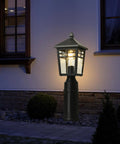 Outdoor scene with Two Pack Dusk To Dawn Outdoor Post Lights With Seeded Glass illuminating a garden near a house at night.
