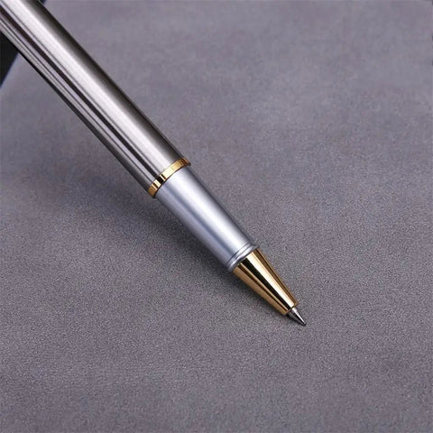 Stainless Steel Golden Rollerball Pen With Smooth Ink Flow And Comfortable Grip on a gray surface close-up.