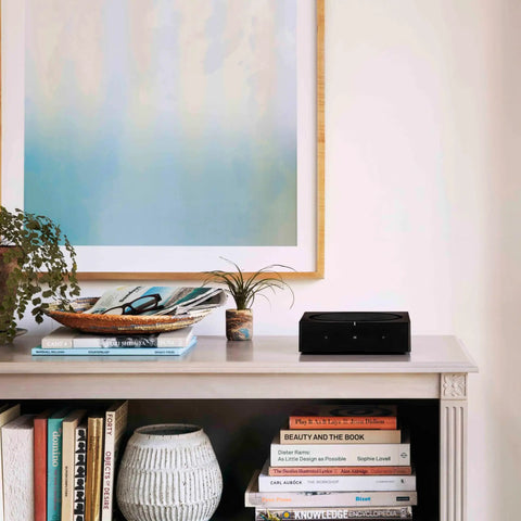 Versatile Home Audio Amplifier For Any Setup From Your Turntable To Outdoor Speakers Powers Vinyl CDs Stored Audio Files And Streaming And Even Expands Your Backyard Entertainment Black on shelf with decor and books
