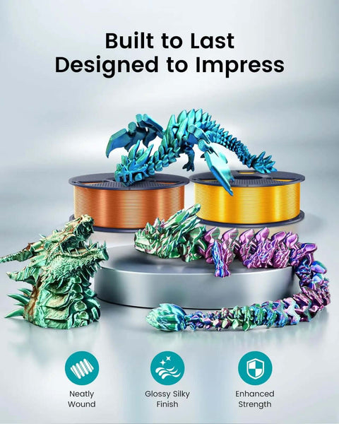 Colorful dragon models in front of spools of Silk PLA Plus Filament 1.75mm 1kg Silver With Chrome Like Gloss Finish And Smooth Silk Texture.