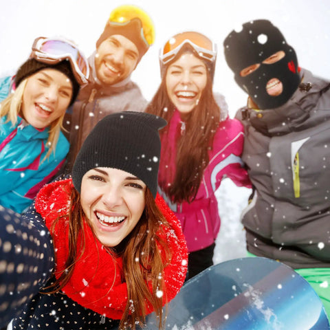 Group smiling in snow; one wearing Three Hole Knit Ski Mask Balaclava for Winter Warmth, full face cover with heart design, outdoor.