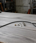 Black Spring-Loaded Gate Latch Cable Pull for Garden Wood Vinyl Fence, includes cable, spring, screw, and hardware on wooden surface.