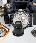 Five Piece Jewelers Loupe Set With Holder 3X 5X 10X 15X 20X Monocular Magnifiers shown with watch parts and black stand.