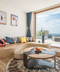 Bright living room with ocean view, round coffee table, cozy seating area, and modern decor accents.